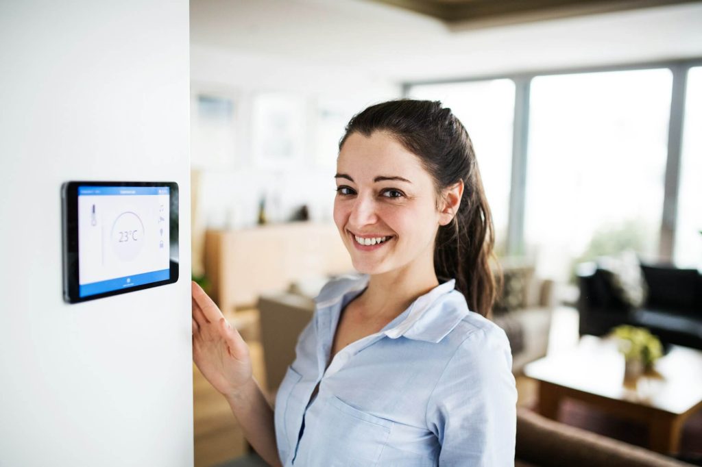 Frau schaut auf ein Tablet mit Smart-Home-Bildschirm