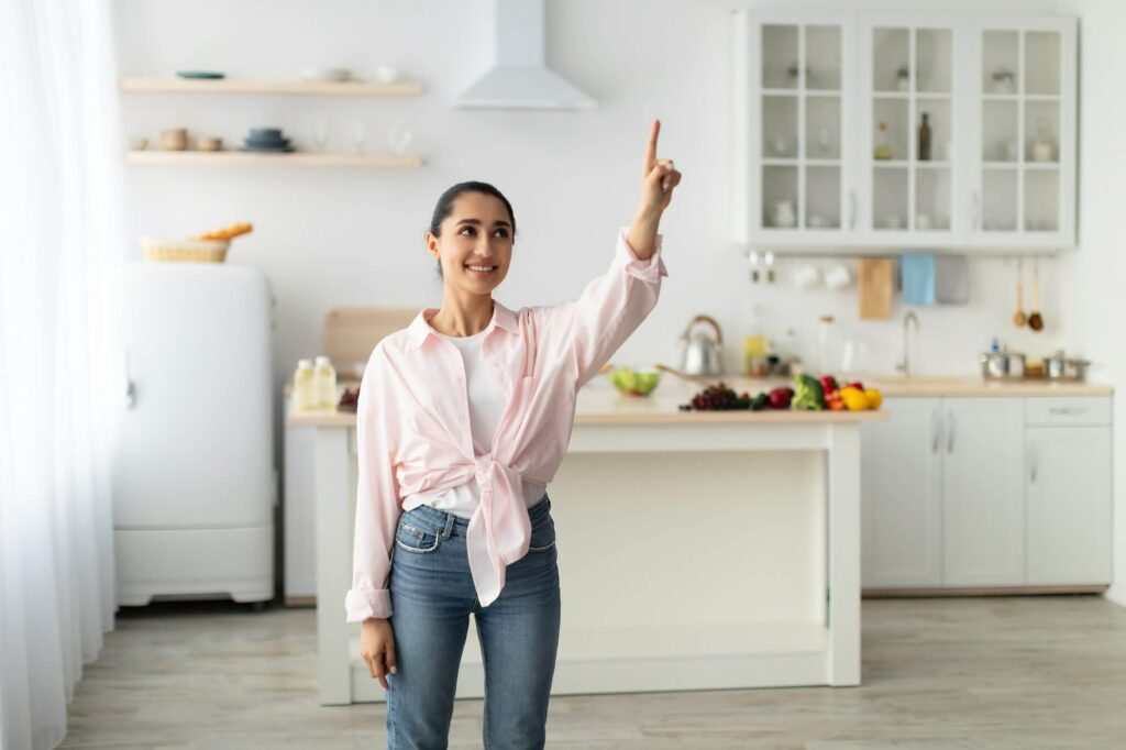 Junge Frau zeigt auf ein digitales Smart-Home-Symbol in der Luft